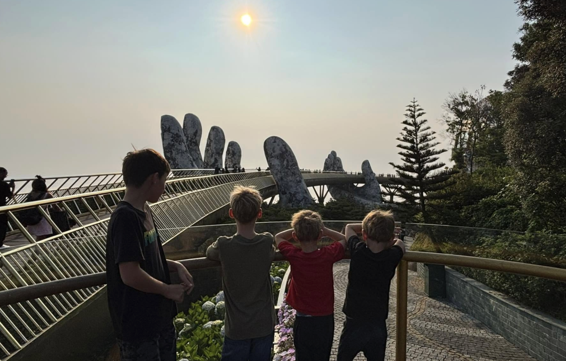The four boys looking out at the Golden Bridge held by giant stone hands in Da Nang, Vietnam